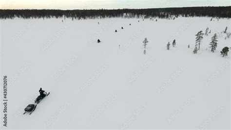 expedition driving on snowmobiles entering lapland forest aerial view drone view of tourism
