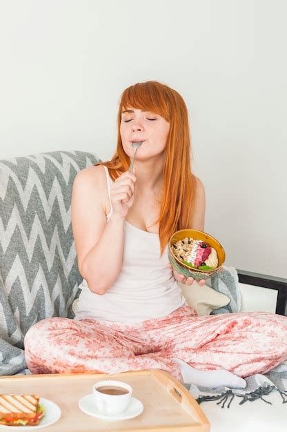Free Photo Young Woman Sitting On Sofa Eating Oat Granola Breakfast