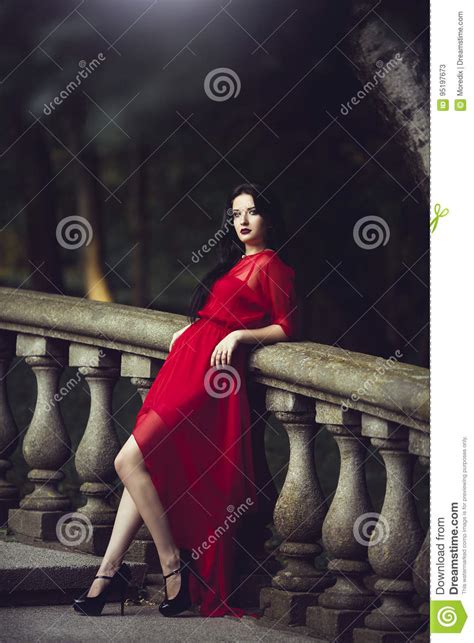 Elegante Sinnliche Sexy Junge Frau Im Roten Kleid Das Nahe Einem Handlauf Aufwirft Stockbild