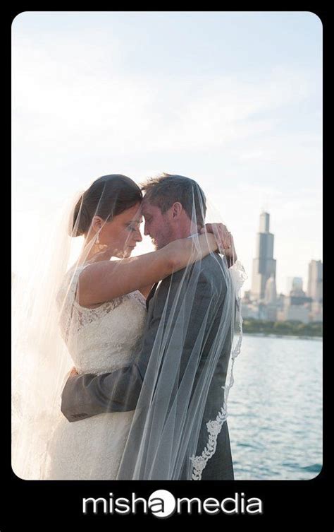 A Bride And Groom Embracing Each Other In Front Of The Water With City