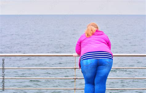 lonely fat girl looks into the horizon of the sea a problem with excess weight concept