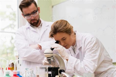 Two Scientist Colleagues Are Using Microscope During Research In A