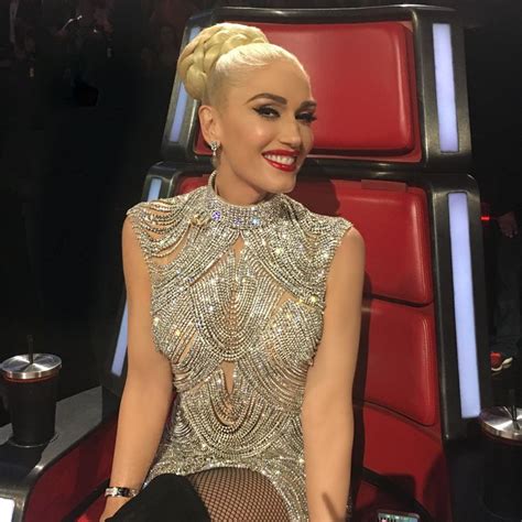 A Woman With Blonde Hair Sitting In A Red Chair And Smiling At The Camera While Wearing Black Gloves