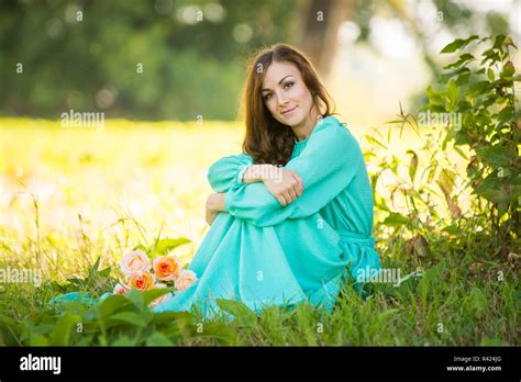 A Beautiful Girl Sitting Under The Shade Of Trees Lies At The Feet Of Her A Bouquet Of Roses