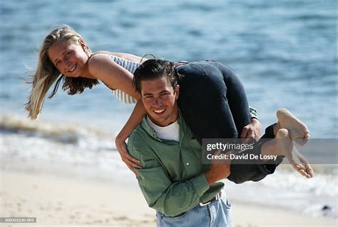 Man Carrying Woman Over Shoulder On Beach Portrait High Res Stock Photo
