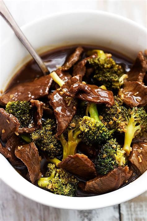 A Bowl Filled With Beef And Broccoli On Top Of A Wooden Table