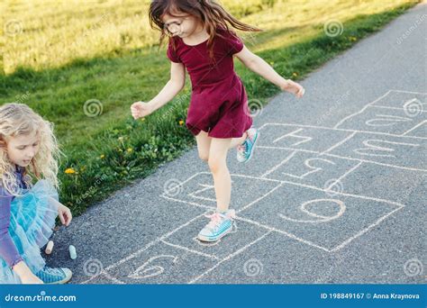 Cute Adorable Children Girls Friends Playing Jumping Hopscotch Outdoors