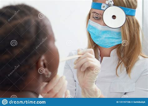 Close Up Of Female Doctor Examining Throat Of African Girl Stock Photo