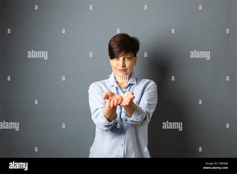Woman Stretches Empty Hands Palms Forward Woman Portrait On A Gray