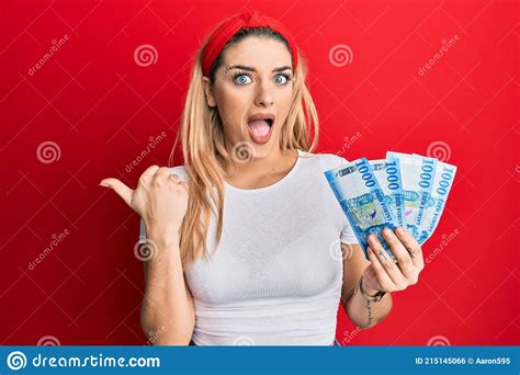 Young Caucasian Woman Holding 1000 Hungarian Forint Banknotes Pointing