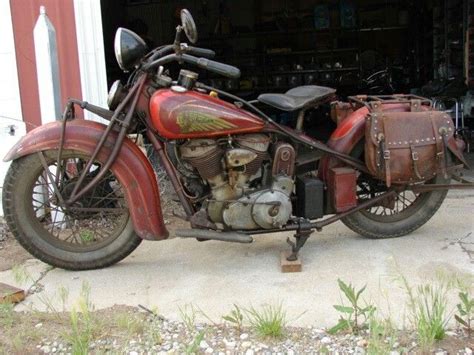 An Old Red Motorcycle Parked In Front Of A Garage