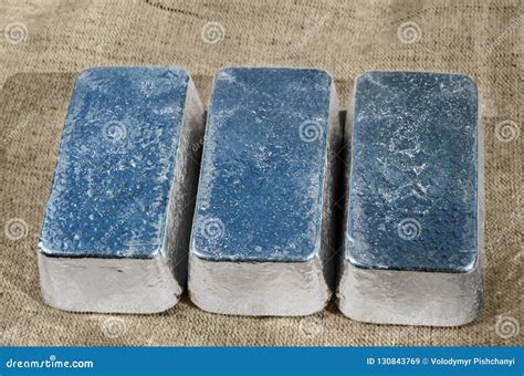 Three Unmarked Silver Bars Against A Rough Textile Texture Stock Image