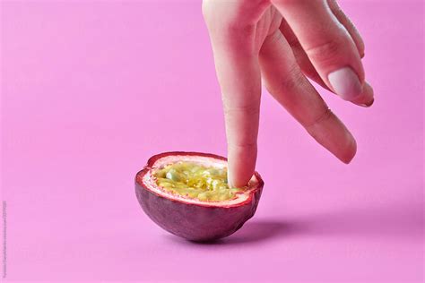 Womans Finger Touch Inside Passion Exotic Fruit On A Pink Background Simulation Of
