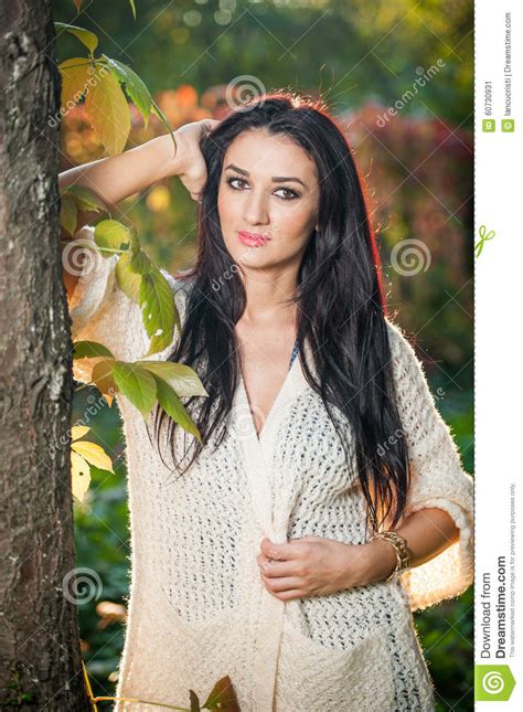 白色摆在的美丽的妇女在秋季公园 年轻深色的妇女在秋天的花费时间在一棵树附近在森林里 库存图片 图片 包括有 女性 生活方式