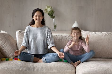 Madre Feliz E Hija Pequeña Practicando Yoga Meditando En El Sofá Foto