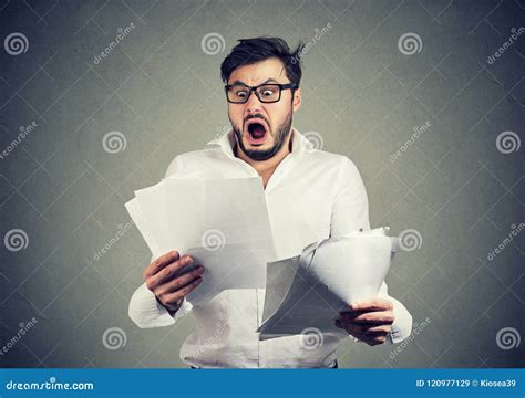 Shocked Business Man Looking Through Papers With Bills Stock Image