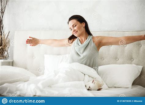 Lazy Morning Concept Beautiful Happy Woman Wakes Up In Bed And Streches Hands Stock Image
