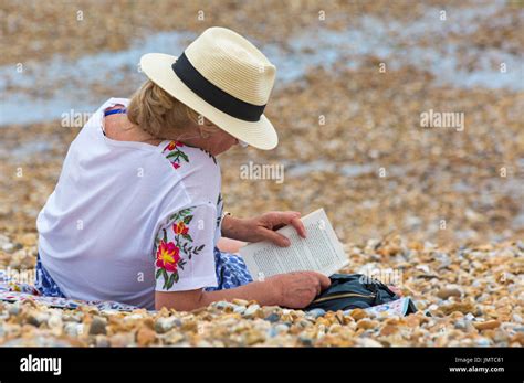 Woman Reading A Book On The Beach At Lyme Regis Dorset In July Stock
