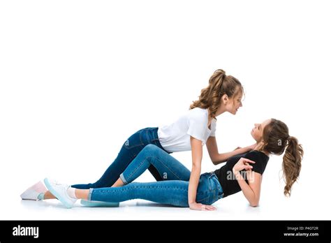 Side View Of Attractive Young Twin Cuddling Lying On Floor Sister On