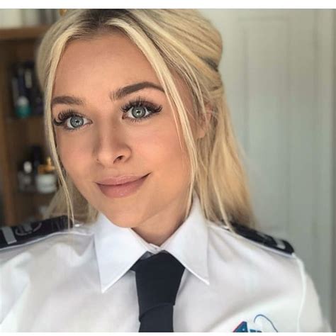 A Female Police Officer In Uniform Posing For The Camera With Blue Eyes And Blonde Hair