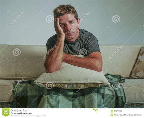 Young Sad And Desperate Man At Home Sitting At Sofa Couch Holding