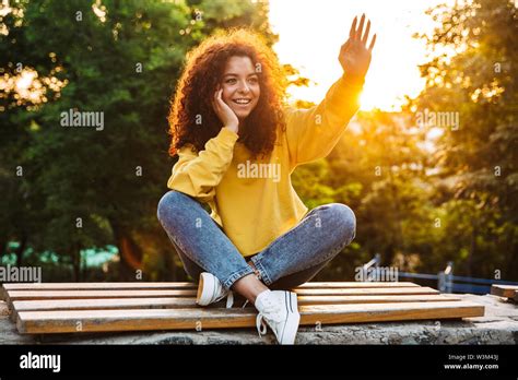 Photo Of A Happy Cute Young Student Curly Girl Sitting On Bench