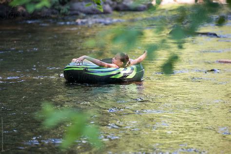 Preteen Girl Floating Down River On Inner Tube By Ronnie Comeau