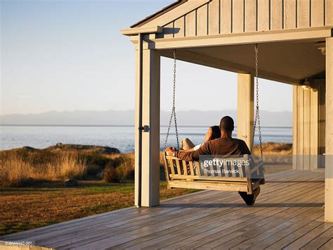 Couple Sitting On Porch Swing Overlooking Water Dusk Rear View Photo