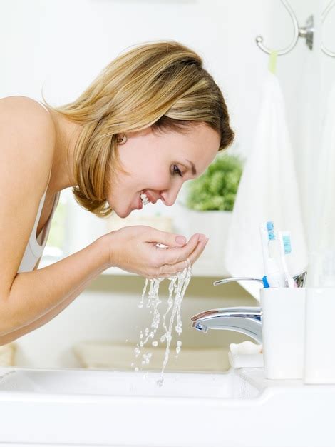 Free Photo Young Happy Woman Washing Face With Water Standing In Bathroom