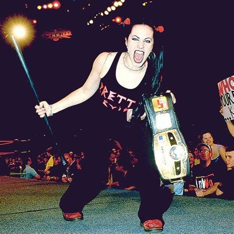 A Woman Holding A Wrestling Belt In Front Of A Crowd