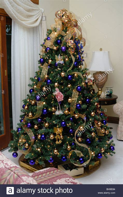 Bring the holiday season's snowy charm indoors! An elegant Christmas tree decorated with gold and blue ...