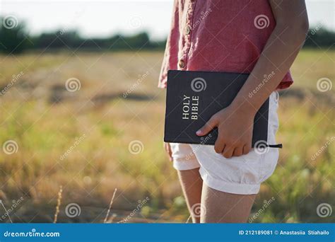 christian girl holds bible in her hands reading the holy bible in a field stock image image