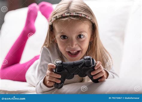 Маленькая девочка играя видеоигры дома Стоковое Изображение