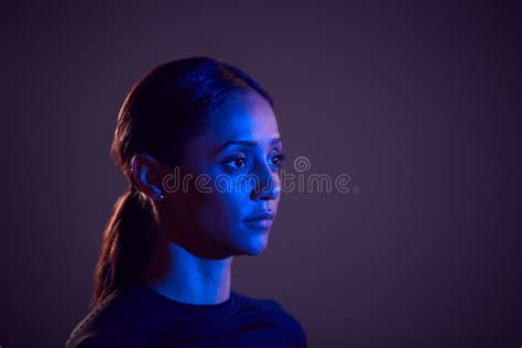 Studio Profile Shot Of Woman With Face Illuminated By Blue Light Stock