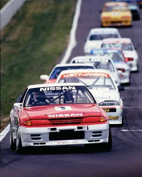 A Group Of Cars Driving Down A Race Track With The Number 1 Nissan On It