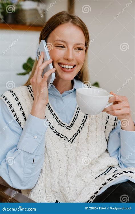 Blonde White Woman Talking On Cellphone While Drinking Tea At Cafe