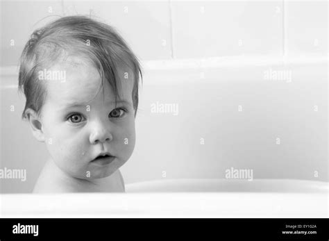 Black And White Portrait Of Baby Girl In Baby Bath Looking At The