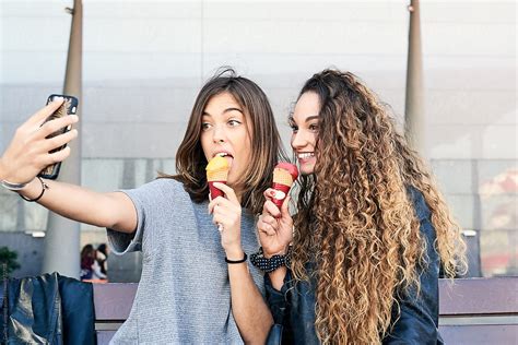 Two Girlfriends Taking Selfie While Eating Ice Cream By Stocksy