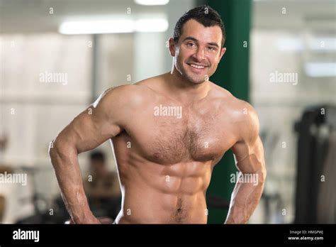 Hairy Healthy Young Man Standing Strong In The Gym And Flexing Muscles