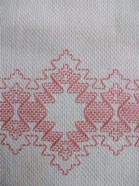 An Embroidered Piece Of Cloth With Red And White Designs