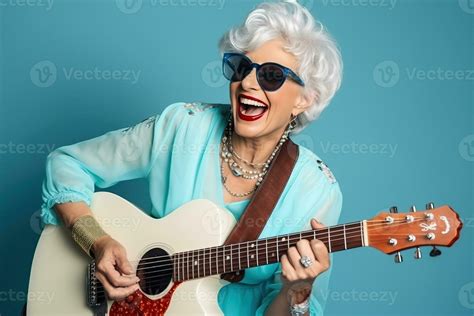 Portrait Of A Cool Trendy Old Woman Playing A Guitar On Blue Studio