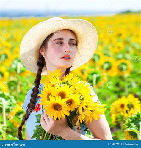 Young Beautiful Woman In A Straw Hat In A Field Of Sunflowers Stock