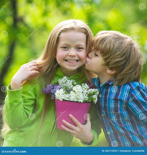 Two Little Children Hug And Kiss Each Other In Summer Garden Kids