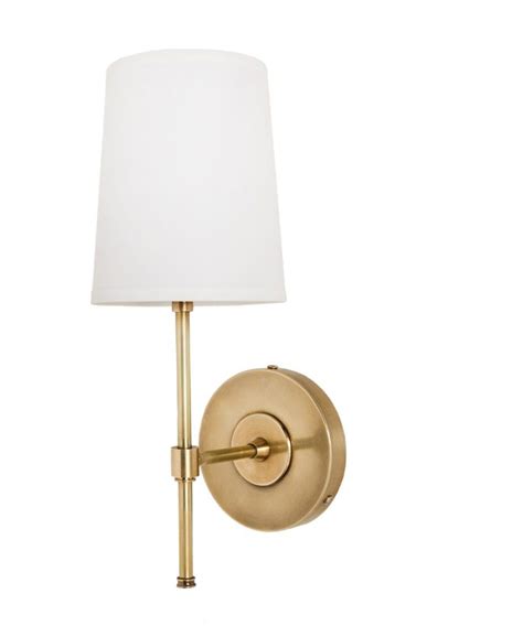 A Wall Light With A White Shade On The Side And A Gold Finish To It