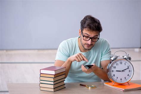Young Male Student In Time Management Concept In The Classroom Stock