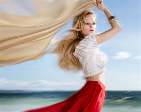 Обои на рабочий стол Девушка в красной юбке и белой блузе стоит на фоне моря и неба фотограф