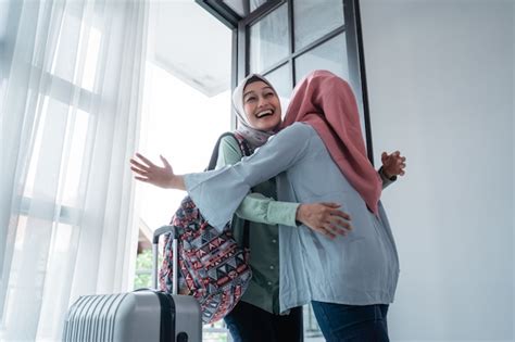 Une Femme Hijab Embrasse Sa Sœur Lorsquelle Se Rencontre à La Porte De La Maison Photo Premium