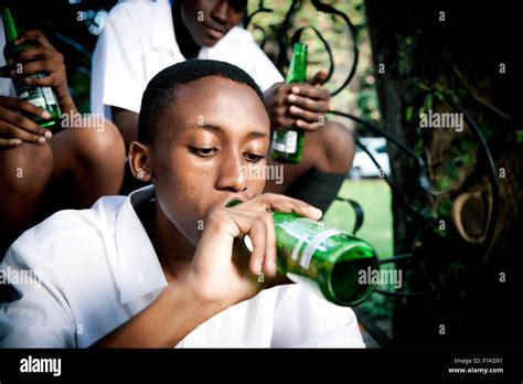 An African Teenage Boy Sitting With His Friends Drinking Alcohol Stock