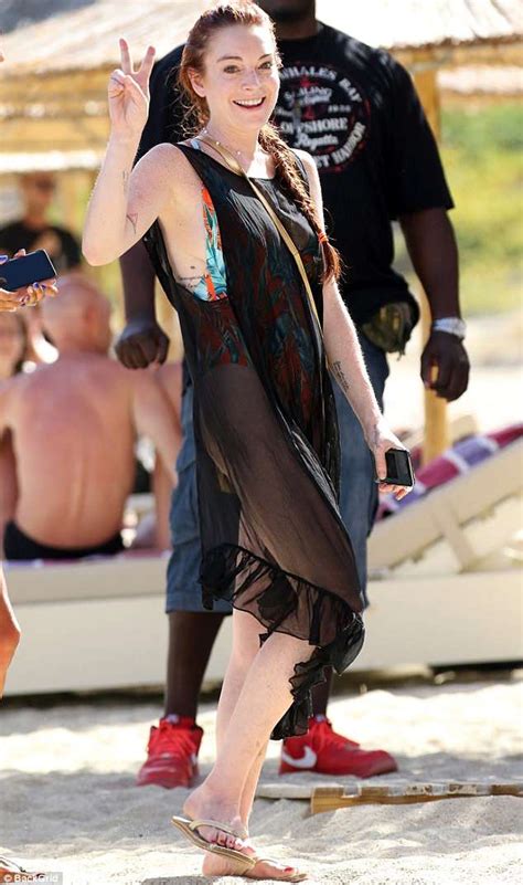 lindsay lohan gives a cheeky flash of her derriere in skimpy swimwear during beach day in