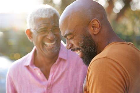 Senior Father Talking And Laughing With Adult Son In Garden At Home